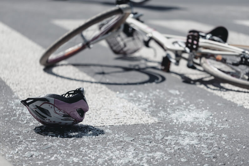 A bicycle and helmet laying on the ground on crosswalk after a bicycle accident 