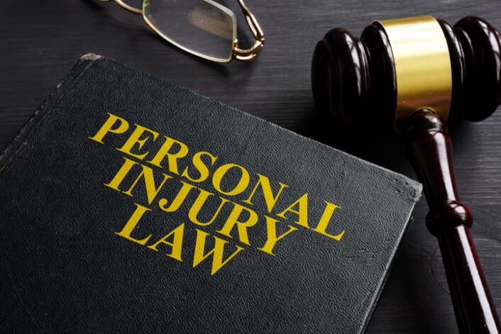 Book showing words personal injury law laying next to judge gavel and eyeglasses