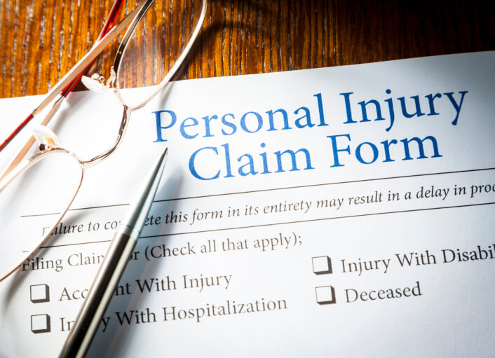 Personal injury claim form with eyeglasses and pen laying on top of claim form