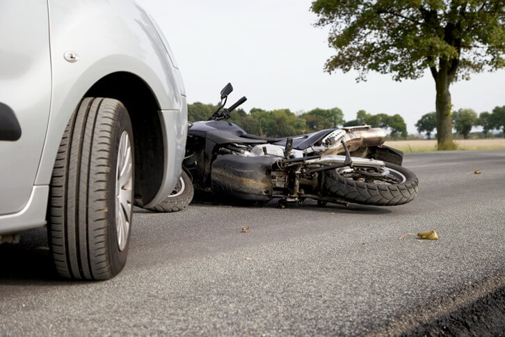 Motorcycle laying in road in front of vehicle after motorcycle accident 