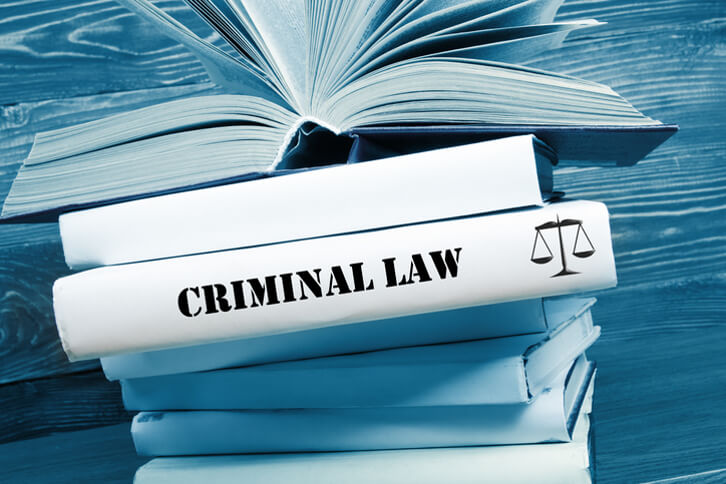 Open book on top of a stack of books with criminal law wording