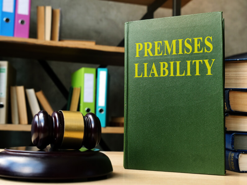 A law gavel laying next to book with the title Premises liability