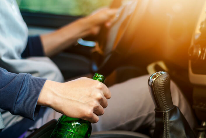 Man drunk driving holding a bottle while driving a car