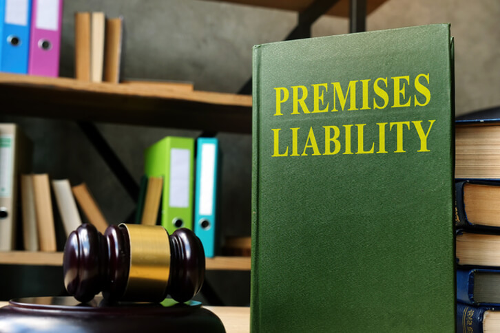 Book titled premises liability on desk next to law gavel and stack of books
