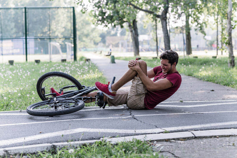 Man on the ground holding knee after bicycle accident 